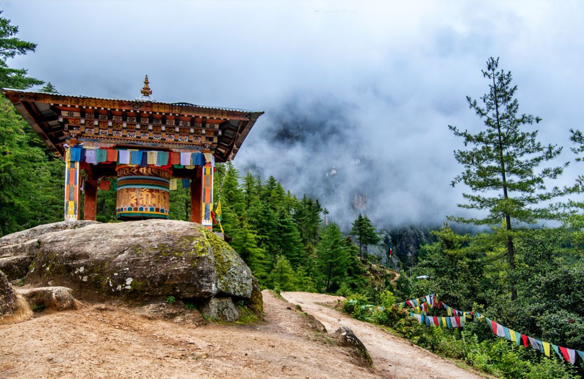 A painted gate and prayer flags on a Bhutanese forest path