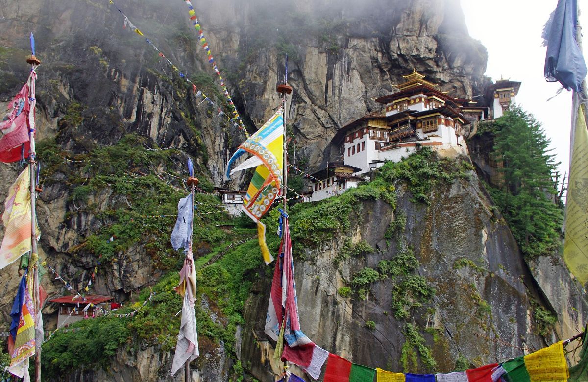 Prayer flags strung across the cliff below Taktsang monastery