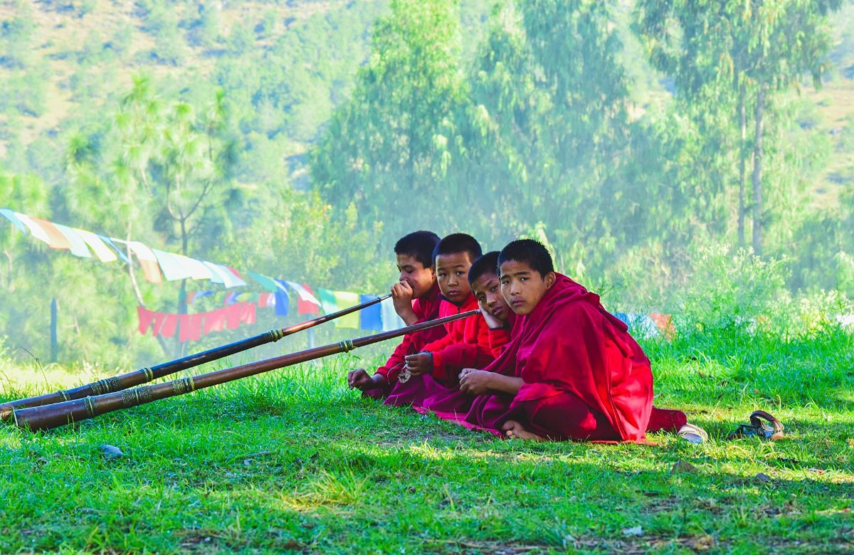 Young monks resting beside prayer flags in a Bhutanese meadow
